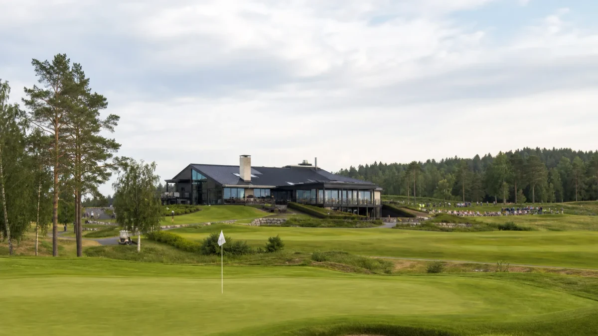 Golfgreen vid ett klubbhus med åskådare på avstånd